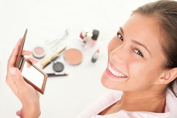 girl looking at a mirror with makeup in front of her